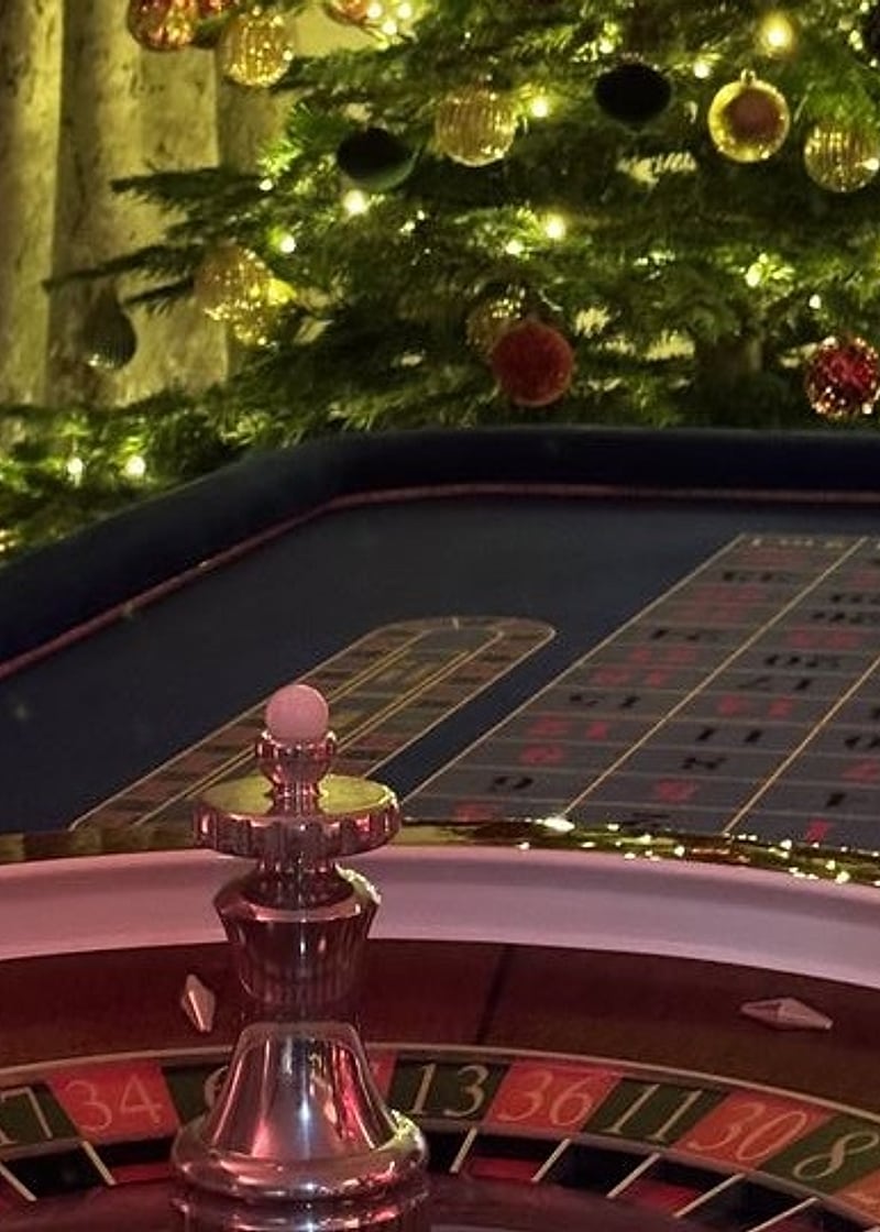 Christmas party casino hire: a Royale roulette wheel beside a lit Christmas tree at a festive party