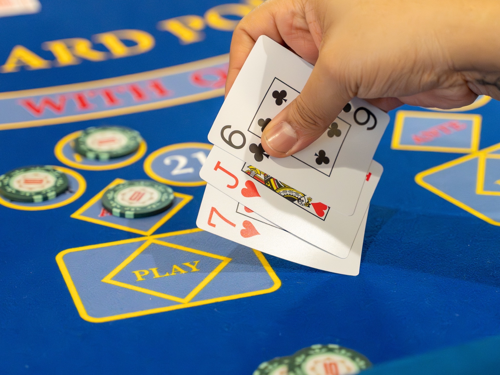 A guest fanning three cards over a Three Card Poker table