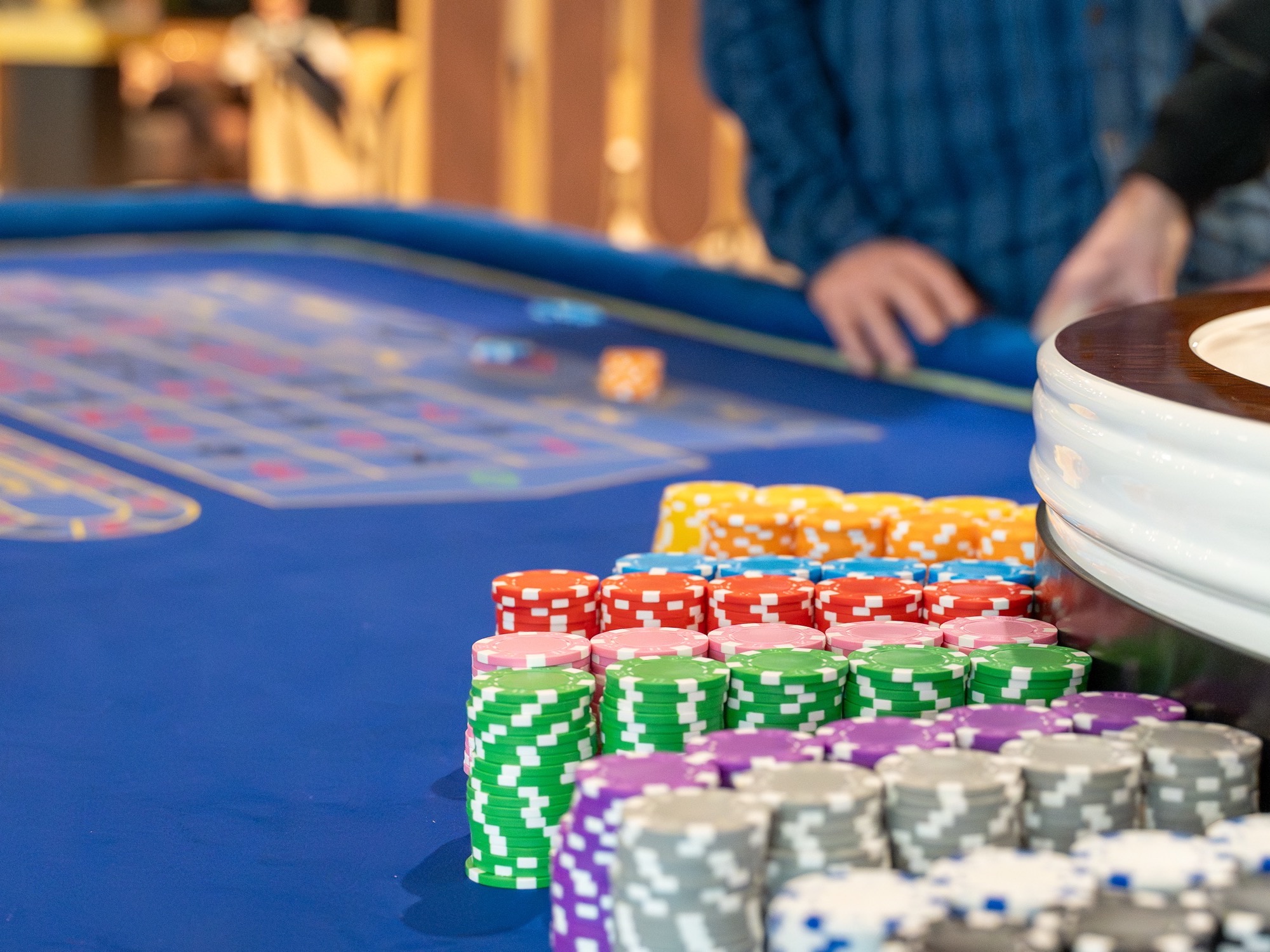 Racked stacks of coloured casino chips beside a roulette wheel