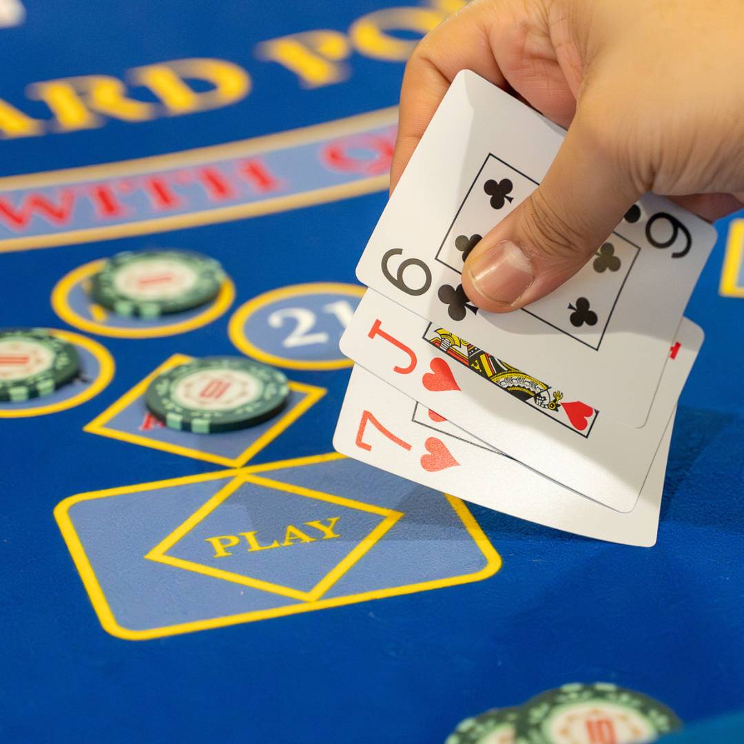 A hand of three card poker held over a Royale table