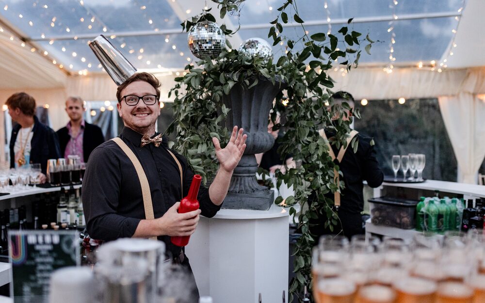 A Mix & Twist bartender flipping a cocktail shaker behind the bar at a marquee event